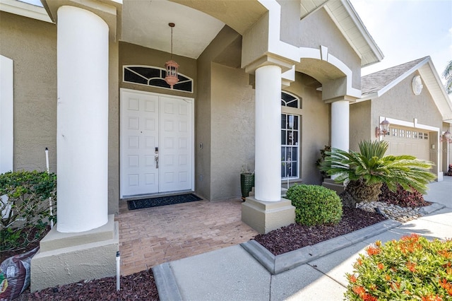 entrance to property featuring an attached garage and stucco siding