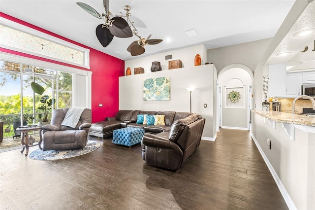 living area featuring baseboards, visible vents, ceiling fan, and dark wood-style flooring