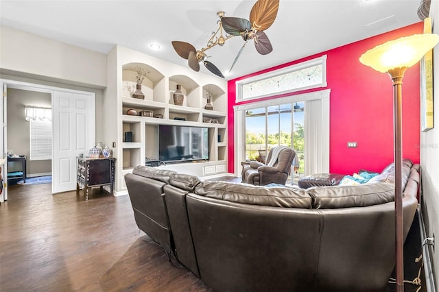 living room featuring dark wood finished floors, built in shelves, and ceiling fan