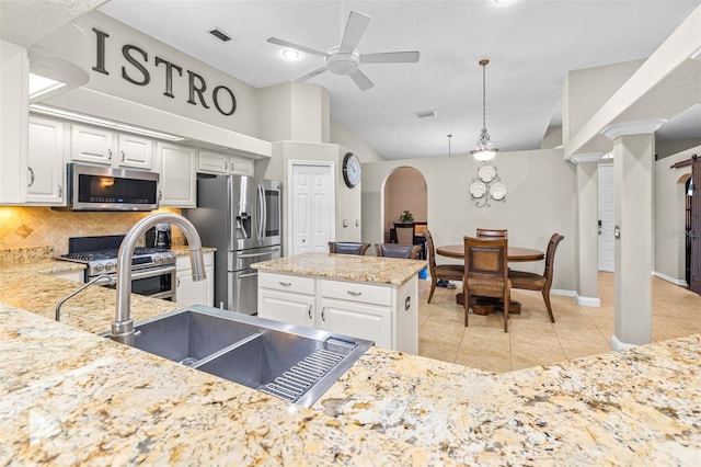 kitchen featuring tasteful backsplash, appliances with stainless steel finishes, white cabinetry, light tile patterned flooring, and lofted ceiling