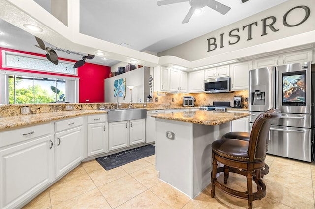 kitchen featuring a sink, light tile patterned flooring, a center island, white cabinetry, and appliances with stainless steel finishes