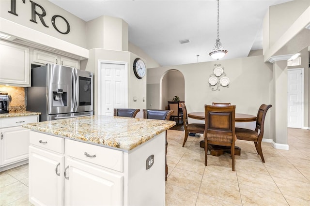 kitchen with stainless steel fridge, a kitchen island, vaulted ceiling, visible vents, and light tile patterned flooring