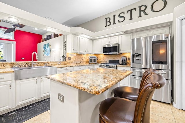 kitchen with light tile patterned floors, stainless steel appliances, a center island, and a sink