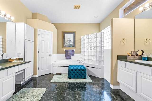 full bathroom featuring two vanities, a bath, a sink, baseboards, and visible vents