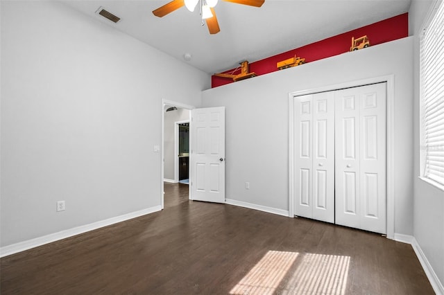 unfurnished bedroom featuring wood finished floors, a closet, visible vents, and multiple windows