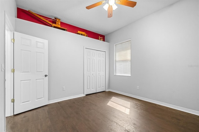 unfurnished bedroom with a closet, ceiling fan, wood finished floors, and baseboards