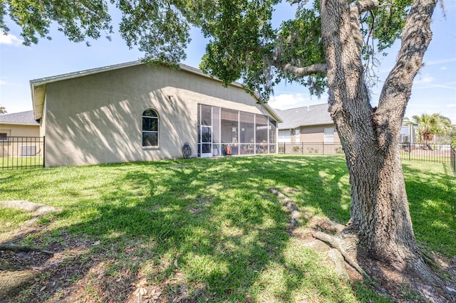 back of property featuring a sunroom, a yard, stucco siding, and a fenced backyard