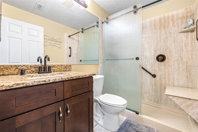 full bathroom featuring a tile shower, toilet, vanity, visible vents, and a textured ceiling