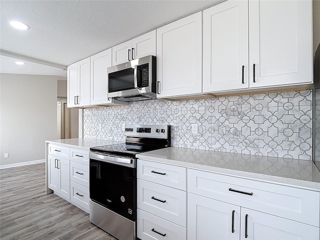 kitchen with baseboards, light wood-style floors, recessed lighting, white cabinets, and appliances with stainless steel finishes