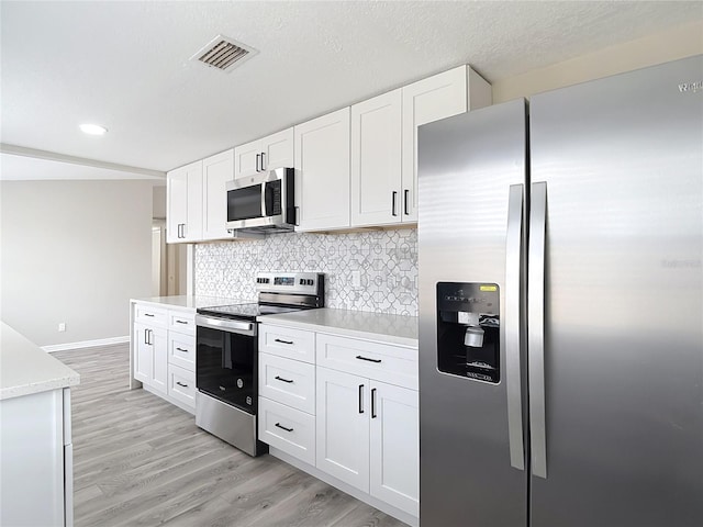 kitchen featuring visible vents, appliances with stainless steel finishes, light wood-type flooring, light countertops, and white cabinets