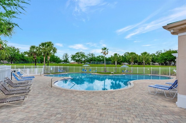 community pool with a patio, fence, and a yard