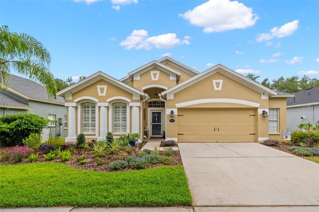 view of front of property with stucco siding, an attached garage, driveway, and a front yard
