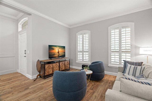 living room featuring baseboards, ornamental molding, a healthy amount of sunlight, and light wood-style floors