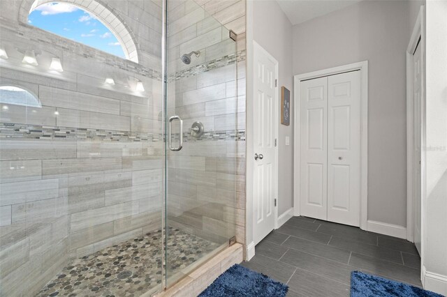 full bath featuring baseboards, a shower stall, and a closet