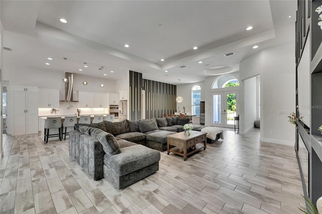 living room with recessed lighting, a raised ceiling, and a high ceiling