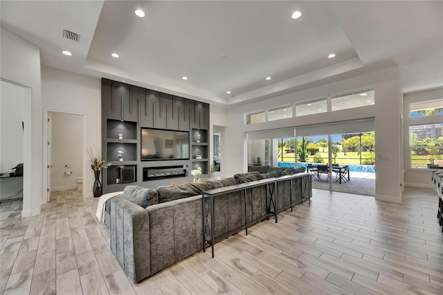 living room featuring a raised ceiling, baseboards, recessed lighting, and visible vents
