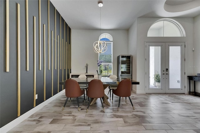 dining room featuring beverage cooler, baseboards, an inviting chandelier, and french doors