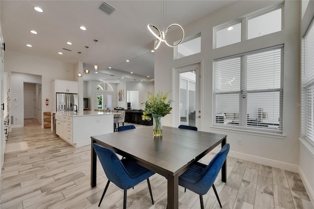 dining room with visible vents, baseboards, a high ceiling, recessed lighting, and light wood-style flooring