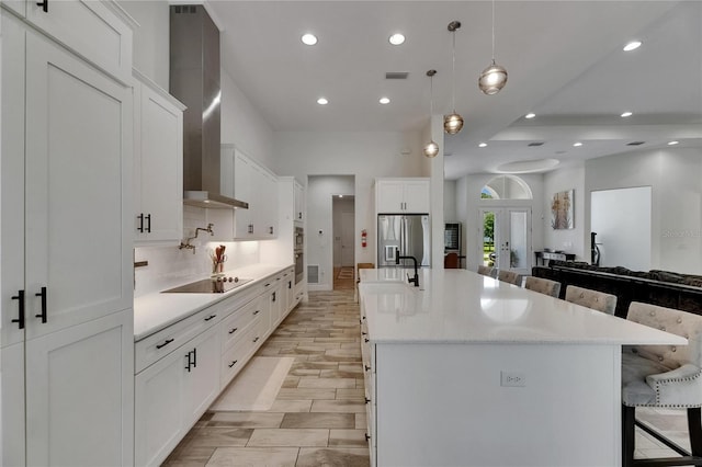 kitchen with wall chimney range hood, recessed lighting, appliances with stainless steel finishes, and a kitchen breakfast bar