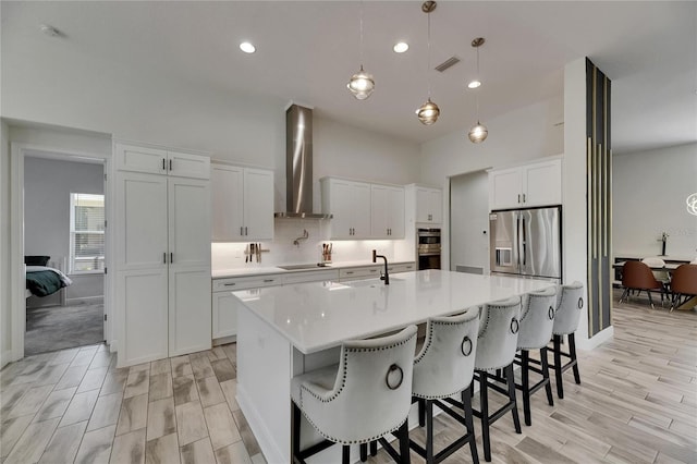 kitchen with light countertops, visible vents, appliances with stainless steel finishes, and wall chimney exhaust hood