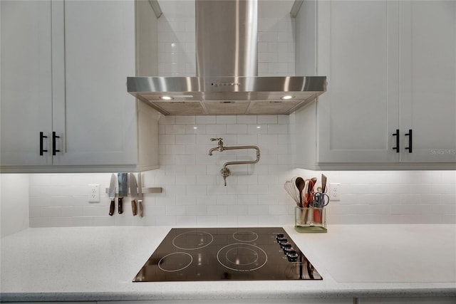 kitchen featuring light countertops, black electric cooktop, ventilation hood, and backsplash