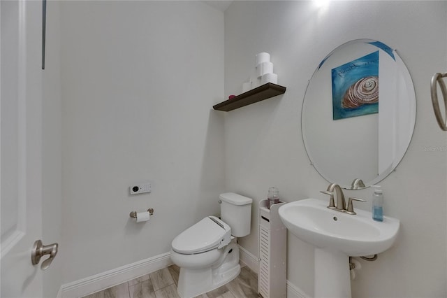 bathroom with baseboards, a sink, wood finished floors, and toilet