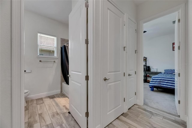 hall featuring baseboards and wood finish floors