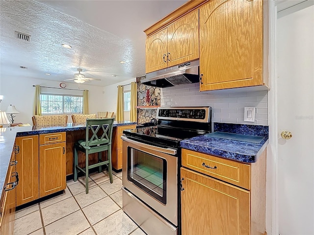 5100 Aragon Way S, Saint Petersburg, FL 33705 - kitchen featuring a ceiling fan, under cabinet range hood, light tile patterned floors, decorative backsplash, and stainless steel range with electric stovetop