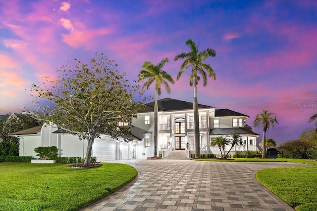 429 St Andrews Dr, Belleair, FL 33756 - view of front of home featuring french doors, curved driveway, a balcony, a lawn, and stucco siding