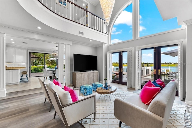 429 St Andrews Dr, Belleair, FL 33756 - living area featuring french doors, a high ceiling, light wood-type flooring, a chandelier, and decorative columns