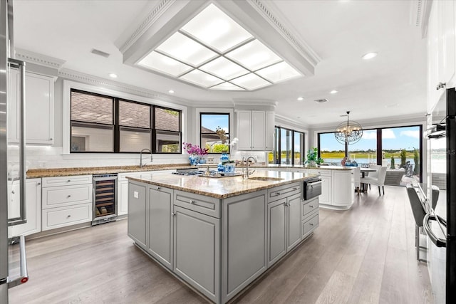 429 St Andrews Dr, Belleair, FL 33756 - kitchen with beverage cooler, a sink, gray cabinets, an island with sink, and ornamental molding