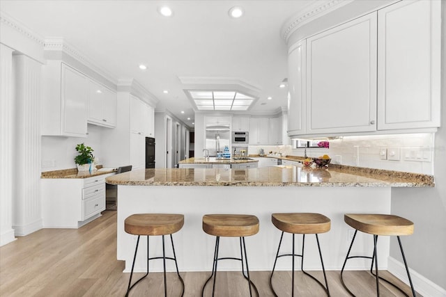 429 St Andrews Dr, Belleair, FL 33756 - kitchen with a peninsula, recessed lighting, light wood-style flooring, white cabinetry, and tasteful backsplash