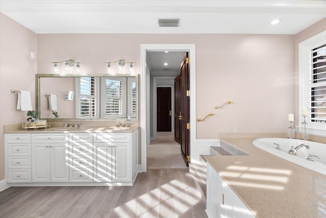 429 St Andrews Dr, Belleair, FL 33756 - bathroom with wood finished floors, double vanity, and a garden tub