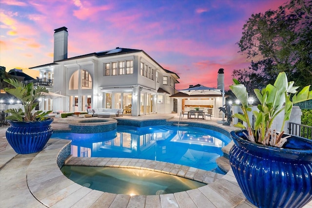 429 St Andrews Dr, Belleair, FL 33756 - back of property featuring a pool with connected hot tub, a chimney, a balcony, and outdoor dining space