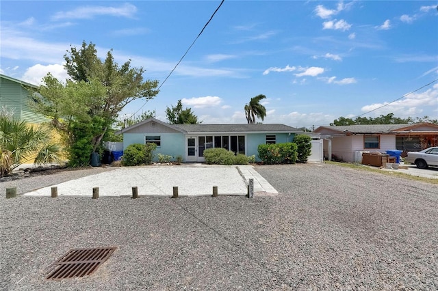 ranch-style home featuring stucco siding and gravel driveway
