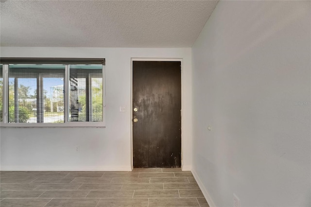 interior space with a textured ceiling, baseboards, and wood tiled floor