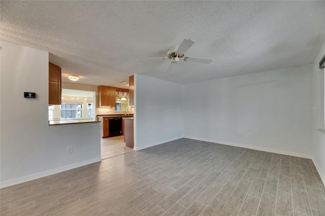 empty room featuring baseboards, a ceiling fan, a textured ceiling, and light wood-style flooring