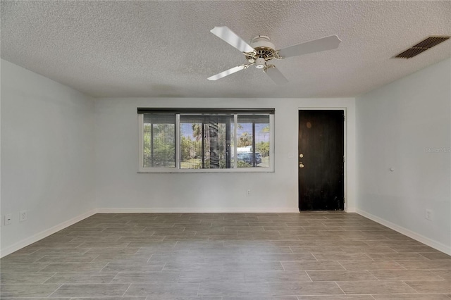 spare room featuring visible vents, wood finished floors, baseboards, ceiling fan, and a textured ceiling
