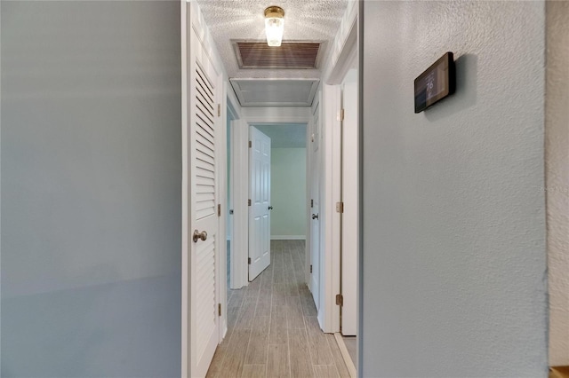 hall featuring baseboards, wood finished floors, and visible vents