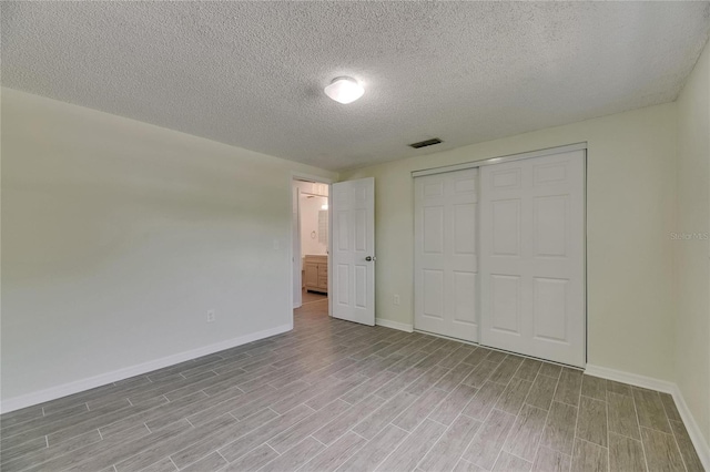 unfurnished bedroom with visible vents, baseboards, wood finished floors, and a closet