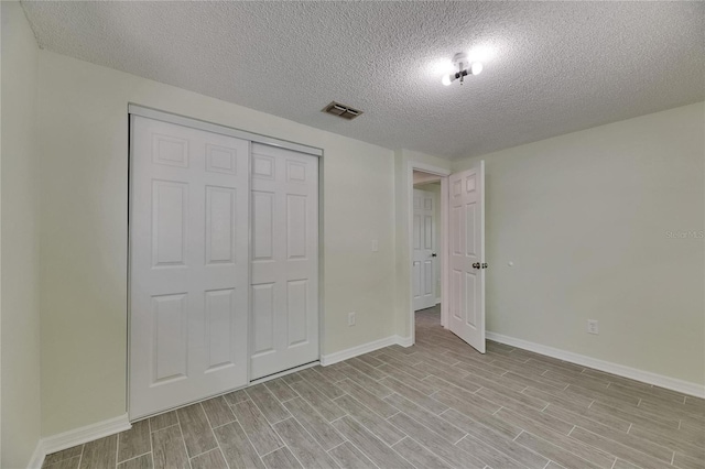 unfurnished bedroom featuring baseboards, light wood-type flooring, and a textured ceiling