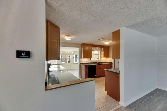 kitchen featuring dark countertops, a sink, dishwasher, a textured ceiling, and stove