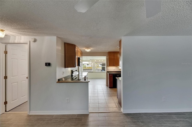 kitchen with a textured ceiling, wood finish floors, baseboards, and brown cabinetry