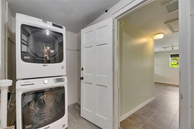 clothes washing area featuring laundry area, tile patterned flooring, baseboards, stacked washer / dryer, and visible vents