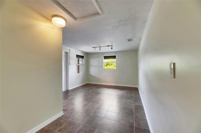 unfurnished room with dark tile patterned floors, baseboards, and visible vents