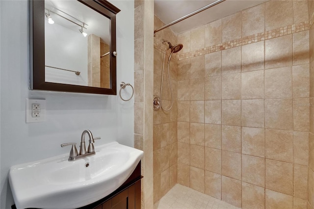 bathroom featuring tiled shower and vanity