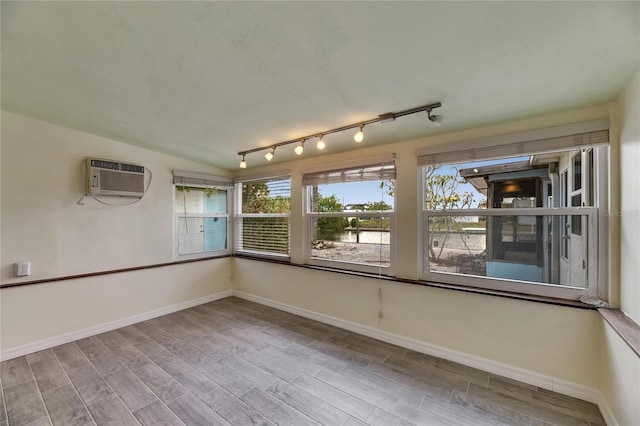 unfurnished room with baseboards, a wall mounted AC, and wood finished floors