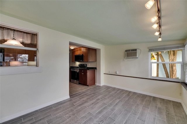 unfurnished living room with baseboards, a wall unit AC, and wood finished floors