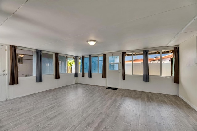 unfurnished room featuring visible vents, baseboards, wood finished floors, and a wealth of natural light
