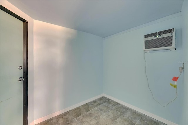 unfurnished room with baseboards and a wall mounted AC
